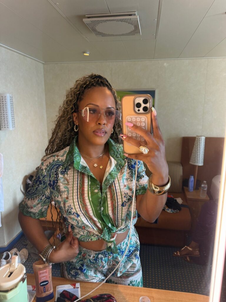Woman in a green and blue patterned matching set taking a mirror selfie.
