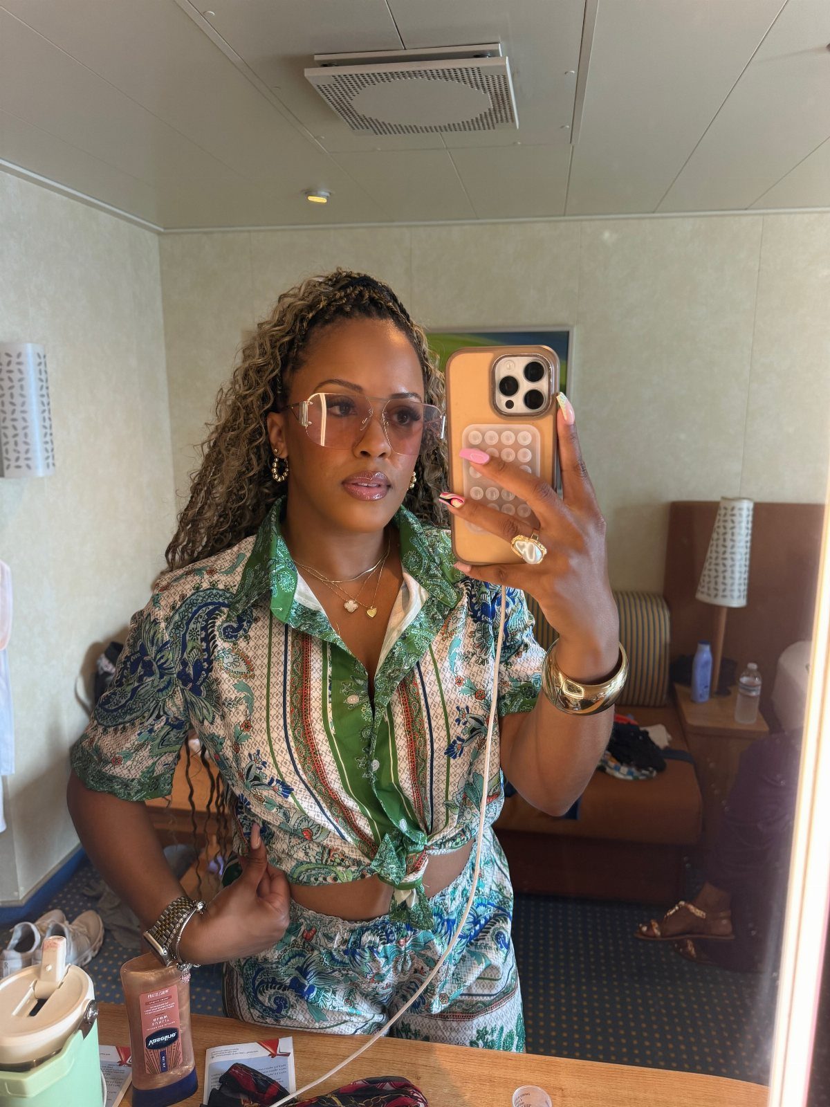 Woman in a green and blue patterned matching set taking a mirror selfie.