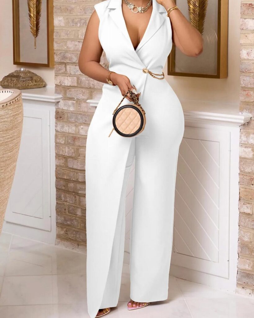 Woman in a white wide-leg jumpsuit with a gold chain belt and round handbag.