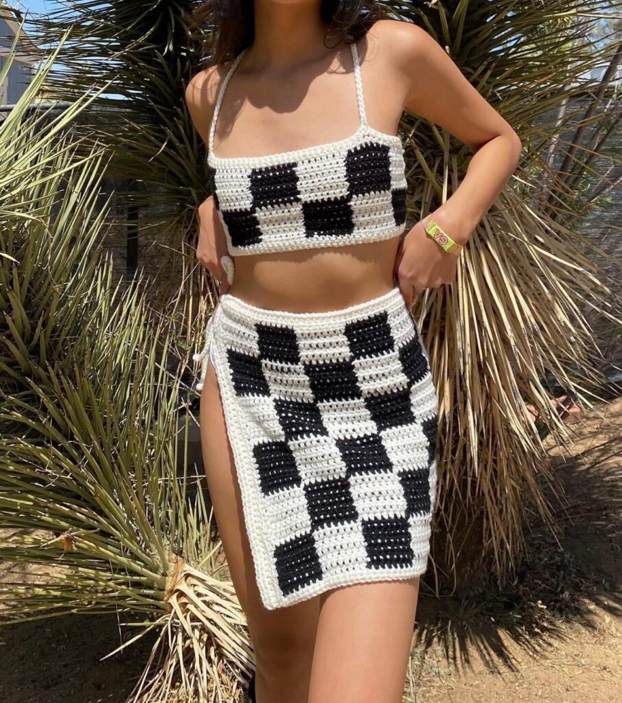 Woman wearing a black and white checkered crochet crop top and matching mini skirt.