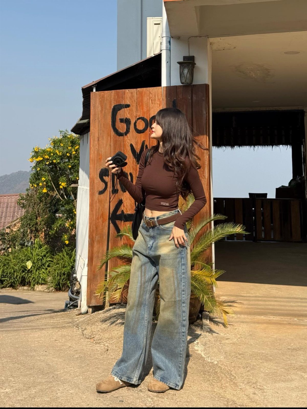 Woman in brown crop top and wide-leg jeans wearing brown suede ankle boots.